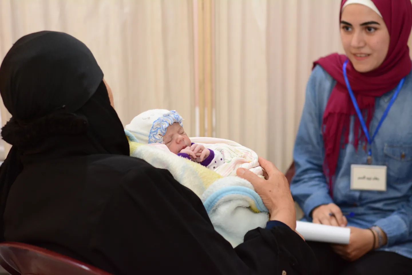 young girl talking to a woman holding a baby 