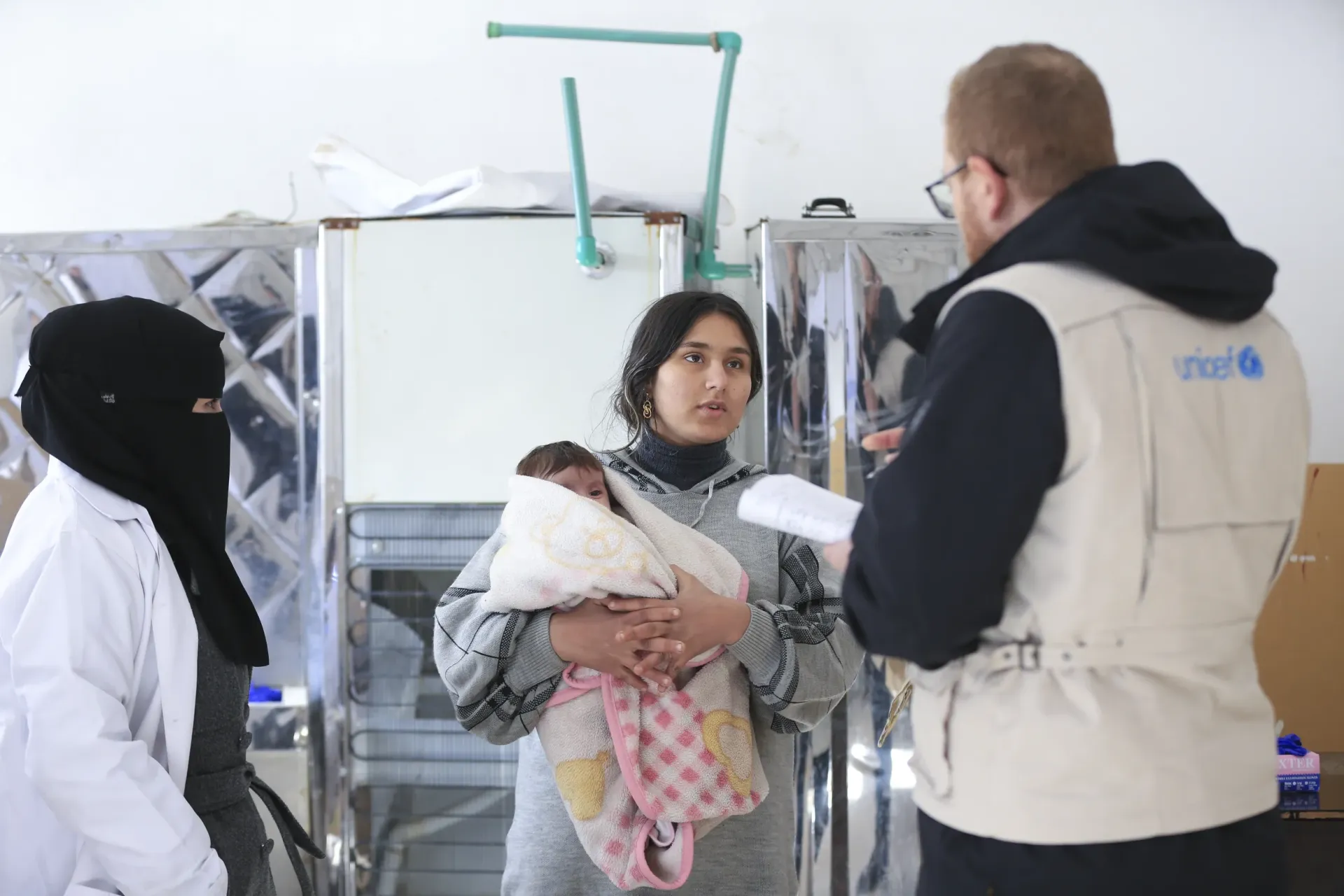 UNICEF health workers listen to a woman holding a baby.