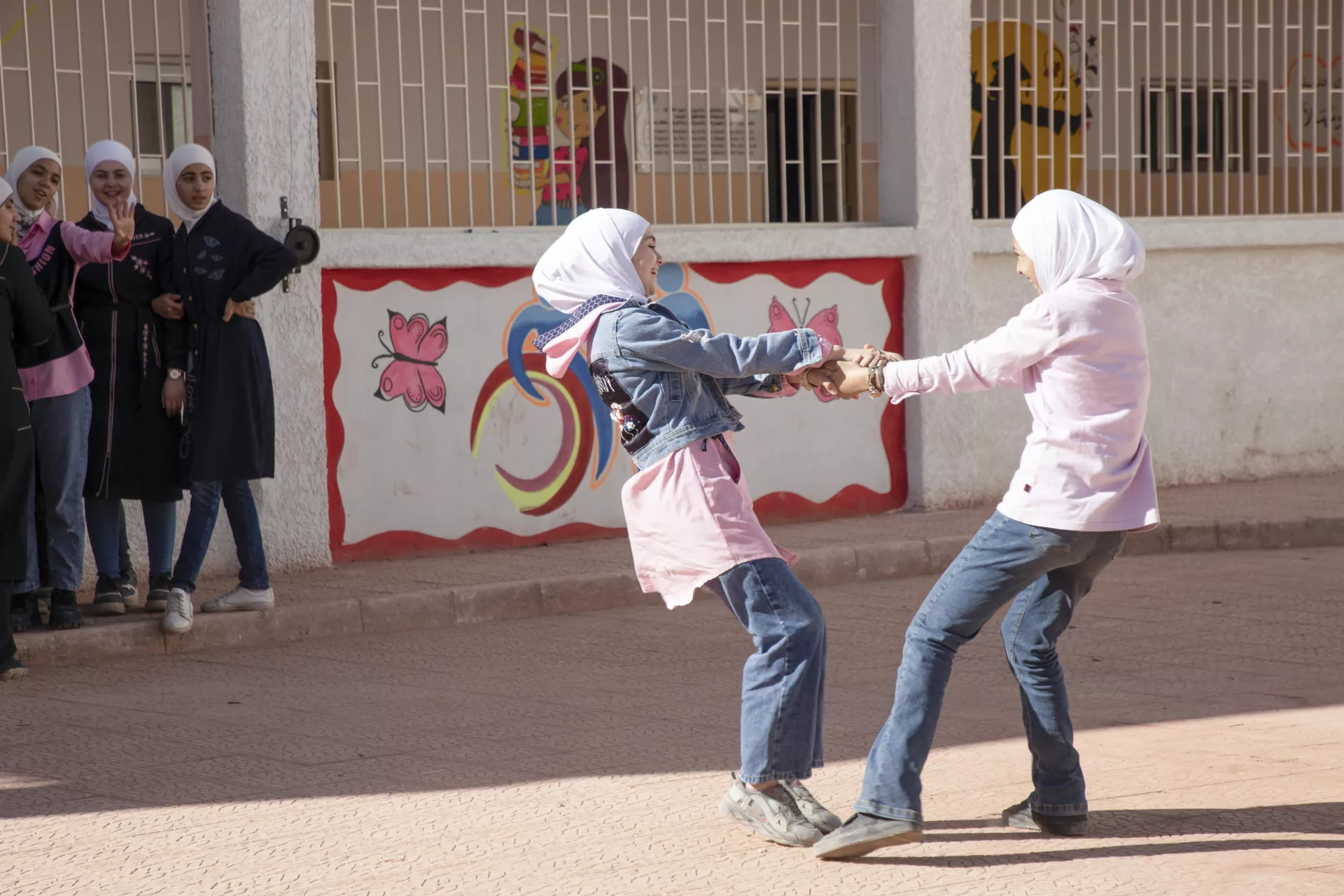 Two girls holding hands spinning around.