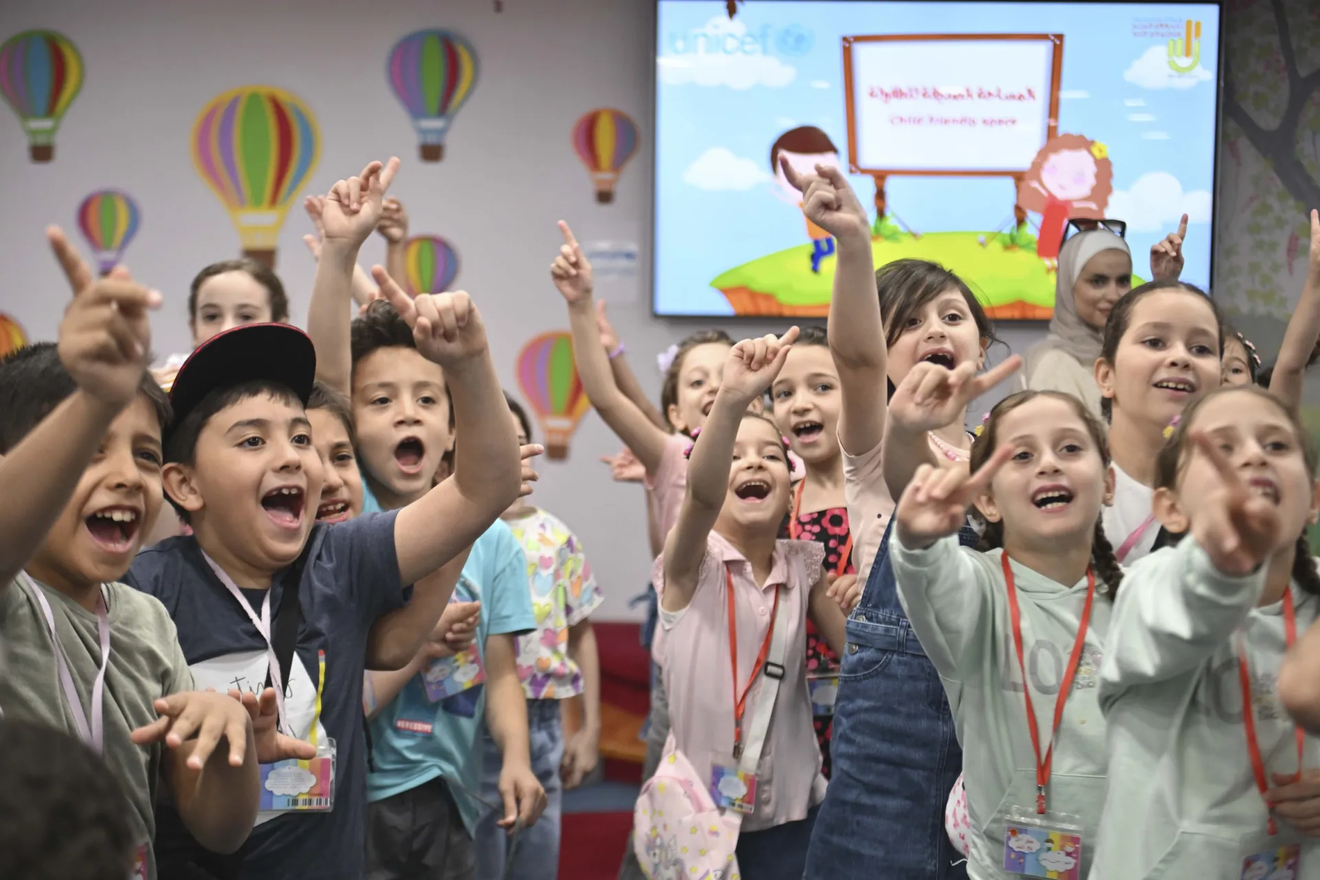 Children take part in a group activity led by a UNICEF-supported youth team to raise awareness about the dangers of remnants of war and the prevention of sexual exploitation at a child-friendly space in Damascus.