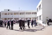 A group of girls hold hands in a big circle, playing in the school yard.