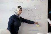 A teacher points at some work on the whiteboard.