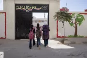 Three girls walk towards the school entrance.