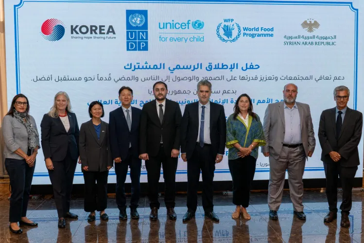 A group of officials standing together in front of a banner with UNICEF, UN and Goverment of Korea logos.