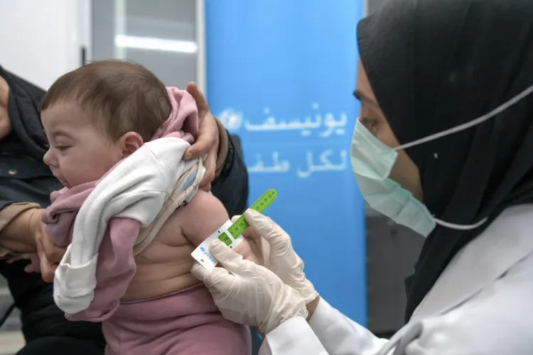 A female health worker measures the upper arm circumference of a healthy baby girl.