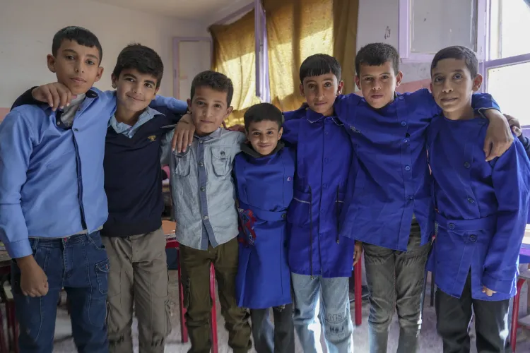 A group of schoolboys stand together in a row with arms over each other's shoulders.