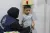A boy stands with his back against a wall with a device resting on his head to measure his height.