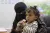 A woman feeds a little girl a supplement from a sachet.