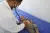 A doctor with a stethoscope bends over a small child who lying on his back on a blue examination table.