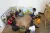 A young man sits crossed-legged with children on the floor, with colourful posters behind them.