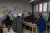 Teachers take part in a group activity, standing around a long narrow table, sorting items on it.