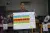 A man holds up a large chart with colourful bars.
