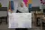A woman holds up a large poster with a colourful chart and handwritten Arabic text.