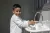 A young boy smiles as he washes his hands in a sink.