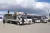 Trucks and cars loaded with belongings are parked in a row.