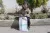 A little girl sits on the curbside with a white bag with a UNICEF logo on it in front of her.
