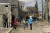 A woman wearing a blue UNICEF coat speaks members of the community on street with a large digging equipment in the distance.