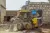 A small yellow bulldozer pushes dirt to fill a ditch.