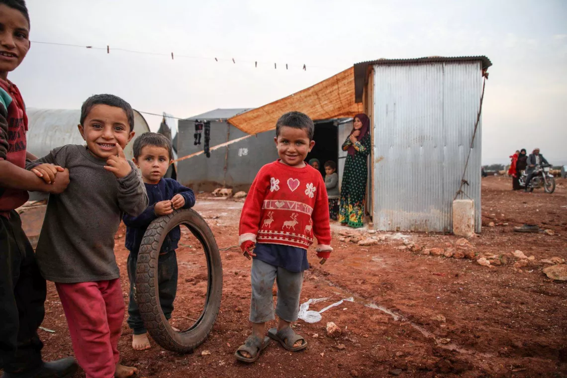 Children play in front of tents in a camp 