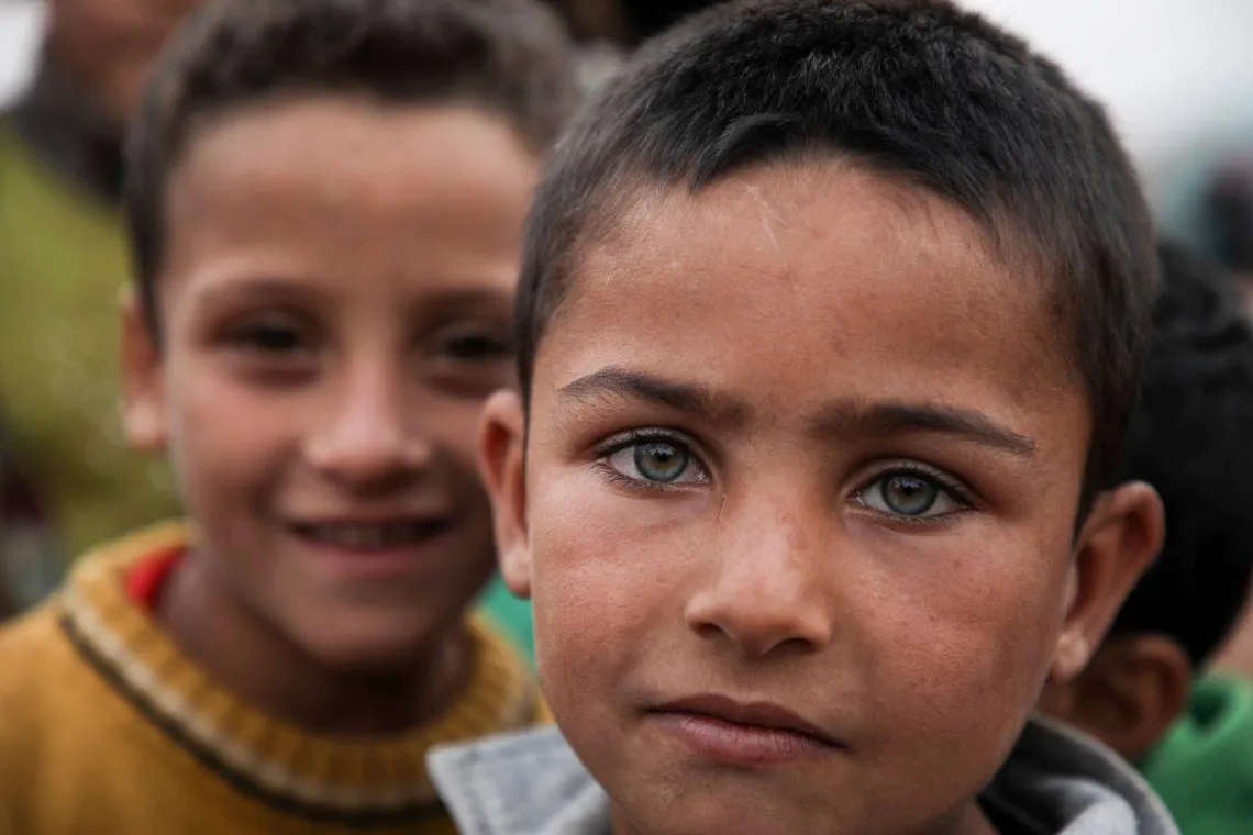 Children play in front of tents in a camp 