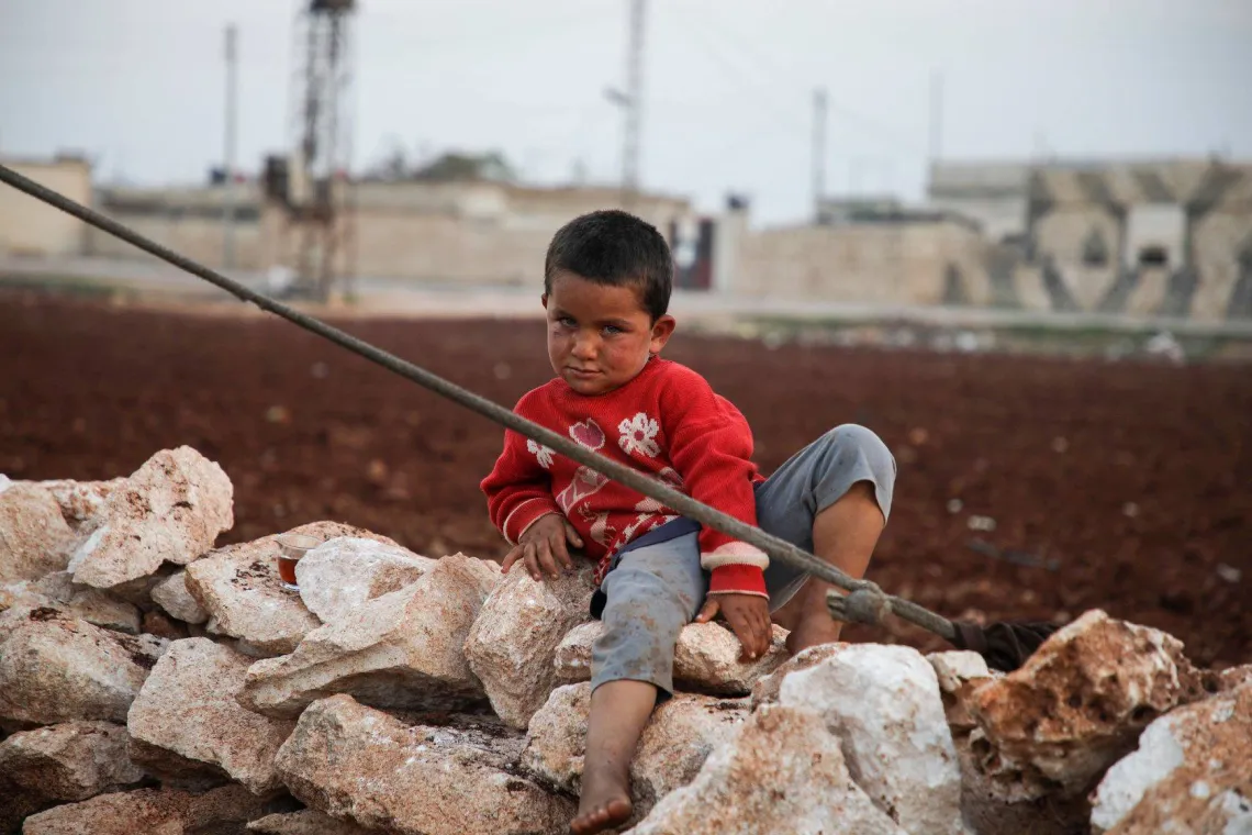 child sitting on stones in a camp
