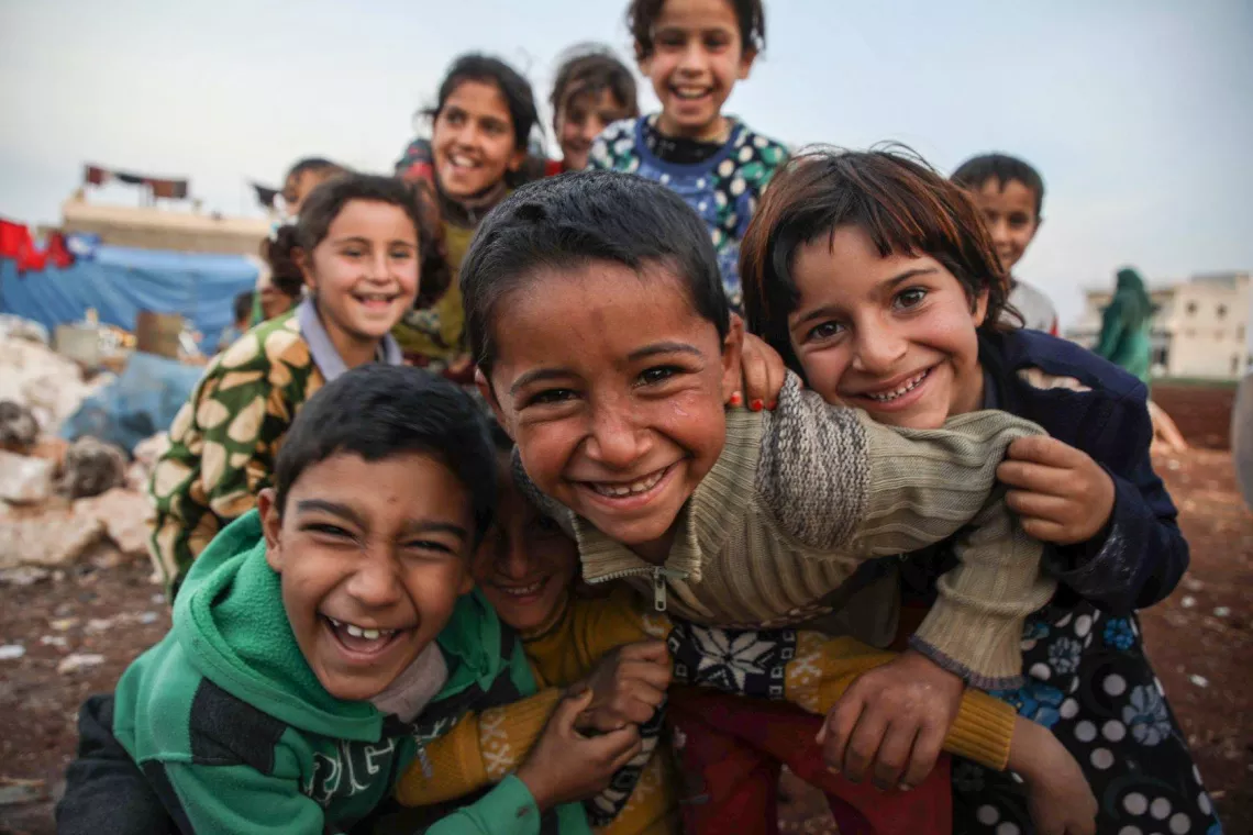 Children play in front of tents in a camp 