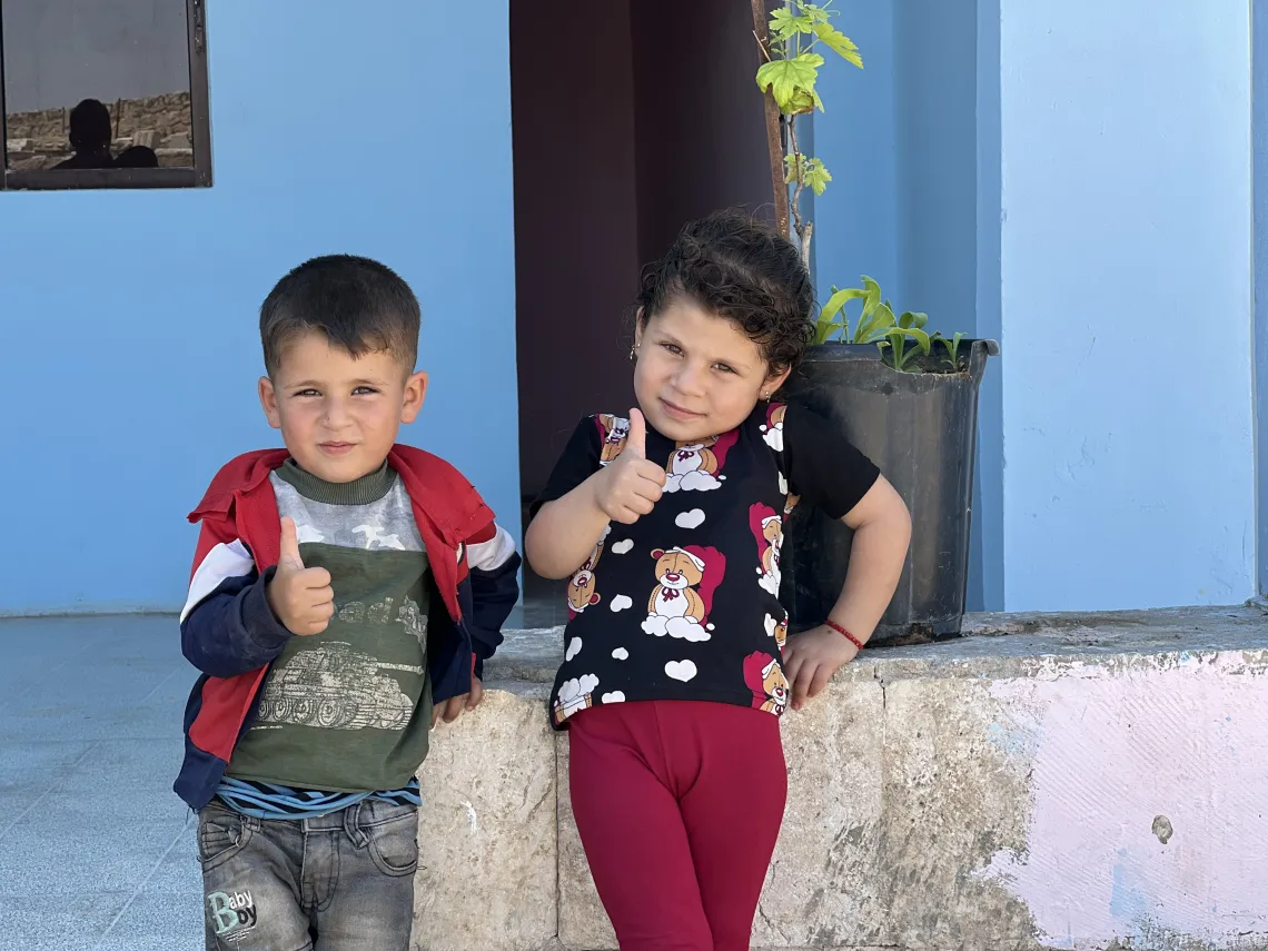Brother and sister sitting on a wall.