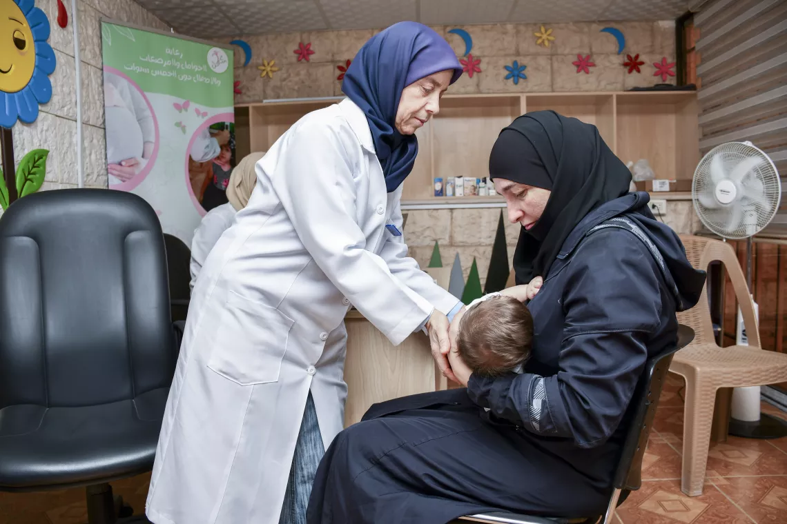 Female doctor shows mother the best position to hold her baby to breastfeed