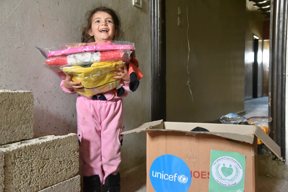 Judi, 6, carries her new clothing, after losing all her belongings in the deadly earthquakes that rocked Syria on 6 February 2023.