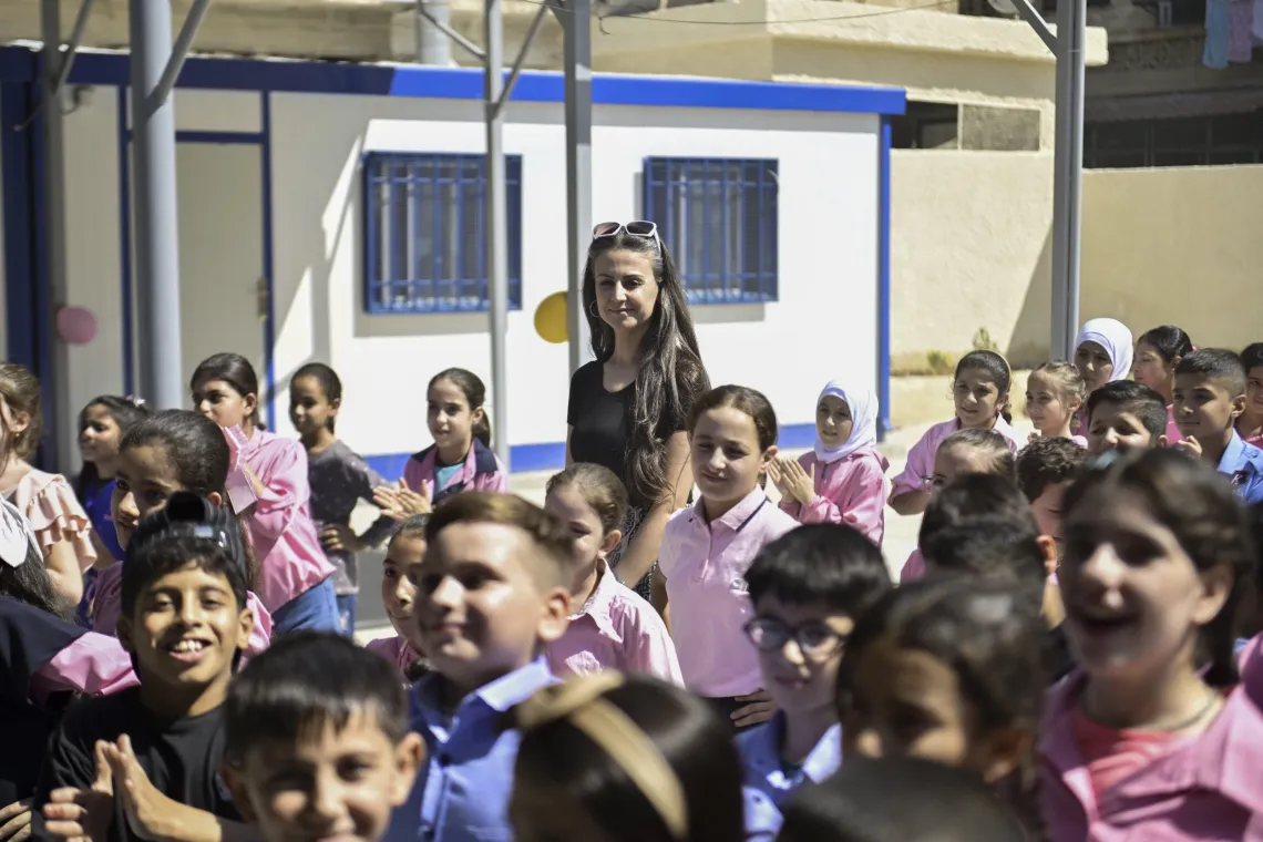 School principal stands behind children during an assembly.