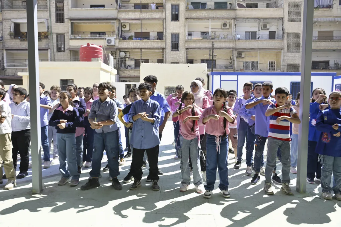 Children take part in physical exercises in a courtyard.