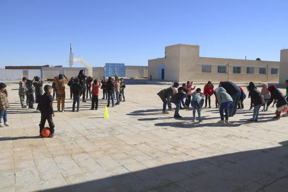 Children do exercises in the playground of their school.