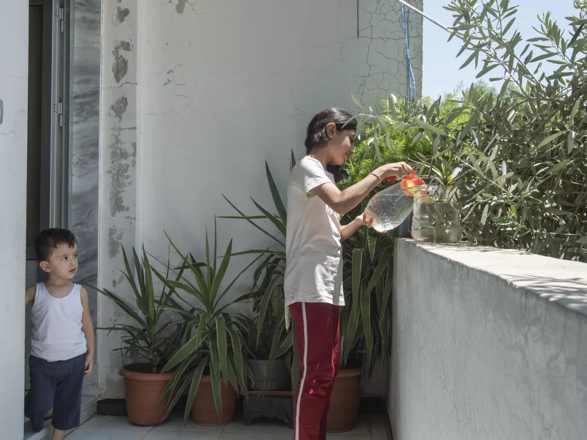 Lana, 12, Leila&rsquo;s granddaughter, waters the plants on her balcony in Western gathering, Kisweh city, Rural Damascus.