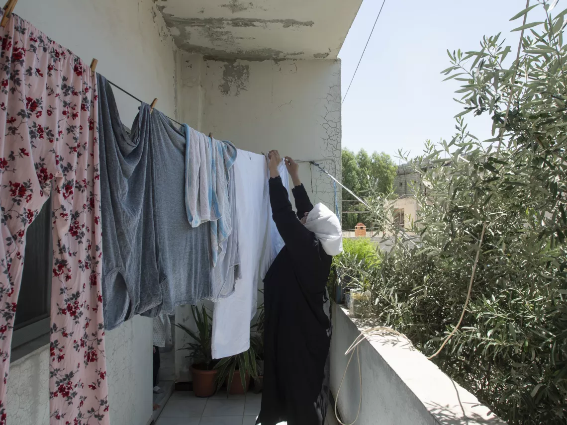 Leila, 63, hangs laundry on the balcony of her house in Western gathering, Kisweh city, Rural Damascus.