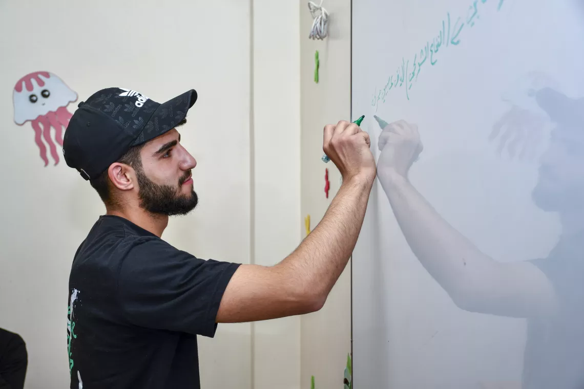 Basheer, 18, engaged in learning, while writing on the whiteboard.
