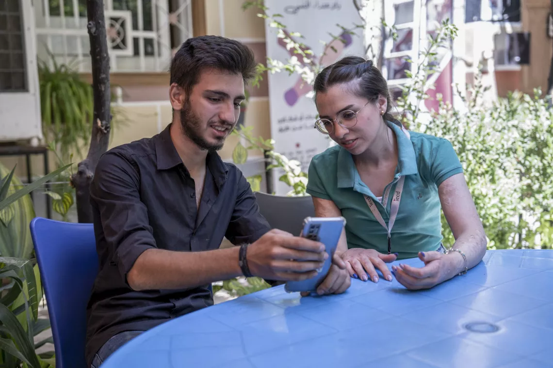 Elia, 17, explains to one of the workers how to fix a mobile phone at a UNICEF-supported youth-friendly space in Jaramana, Rural Damascus.