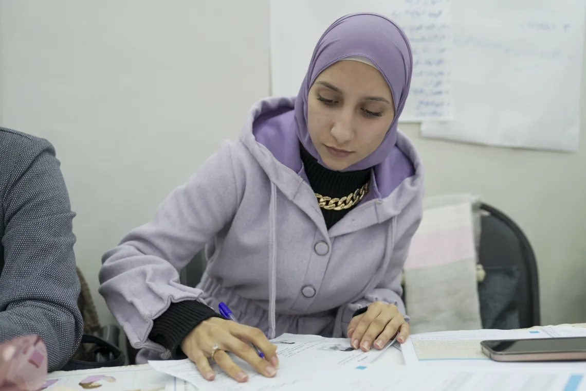 A woman sits and writes notes in a notebook.