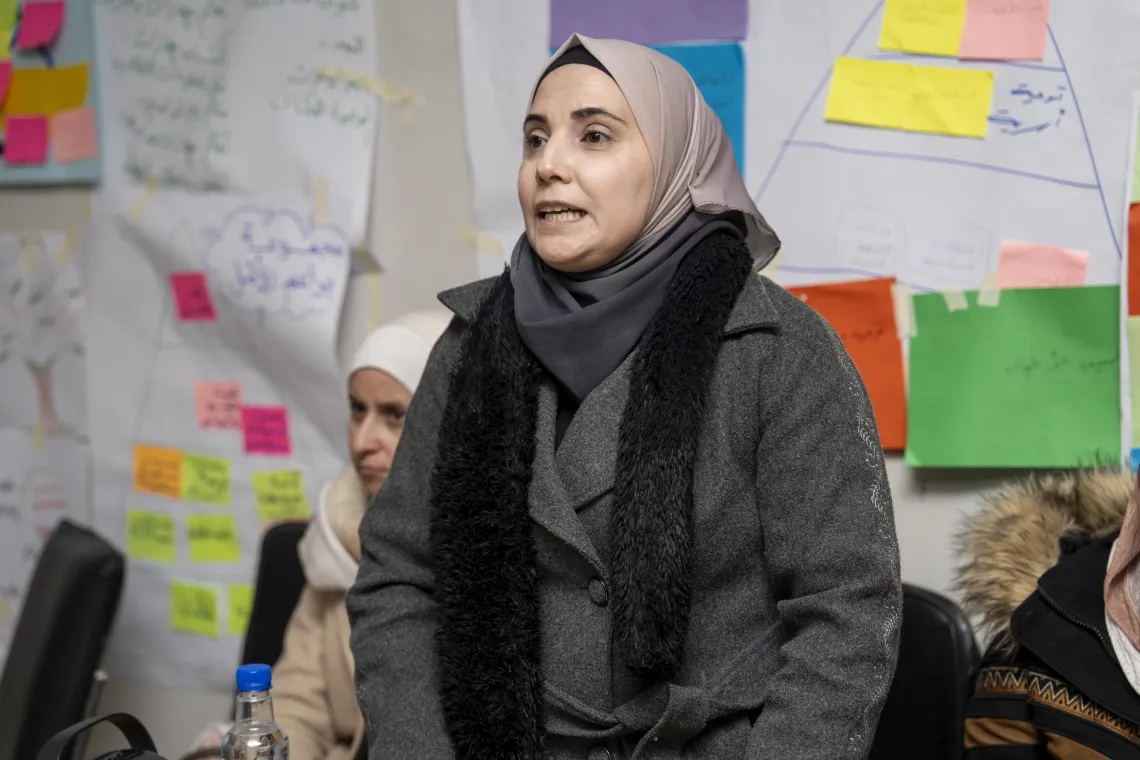A woman stands up in a class while speaking.