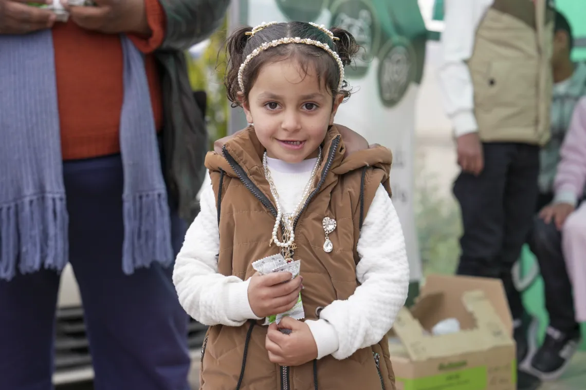 A little girl holding a small package, smiles for a photo.