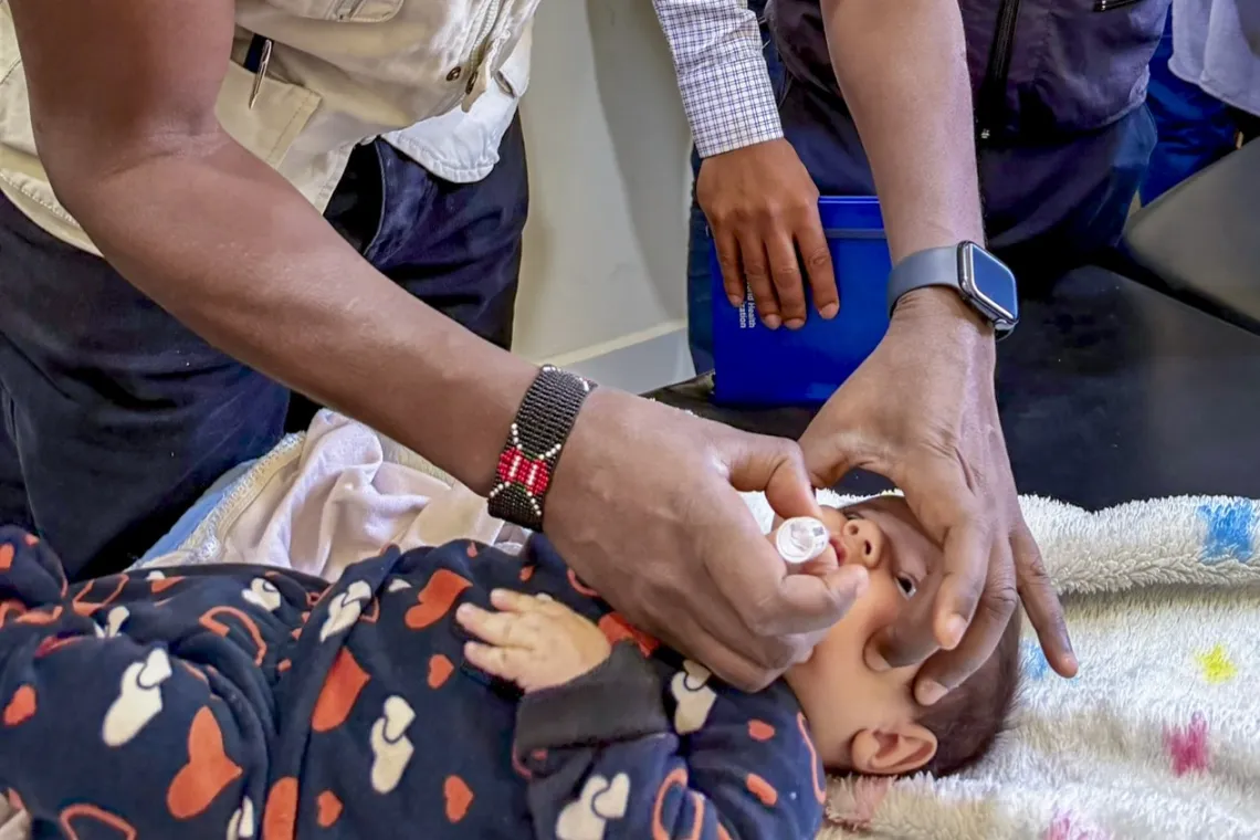 A UNICEF staff member administers an oral vaccine to a child.