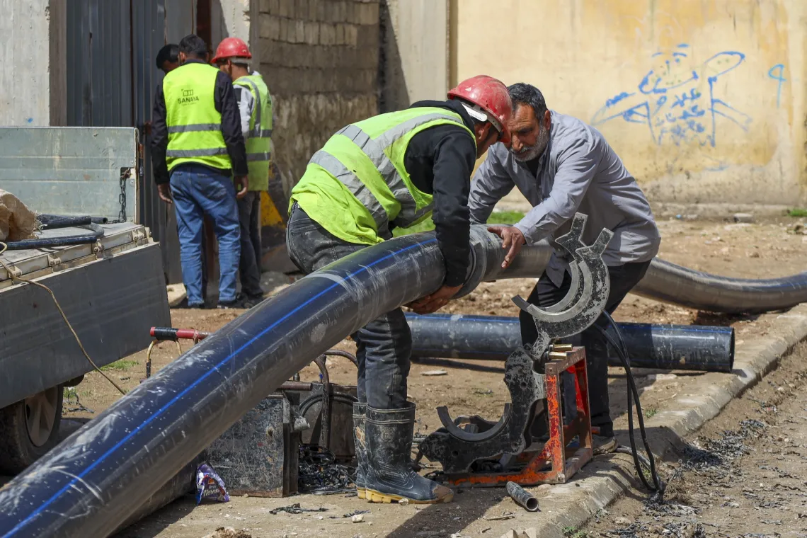 Workers prepare new pipes for installation.
