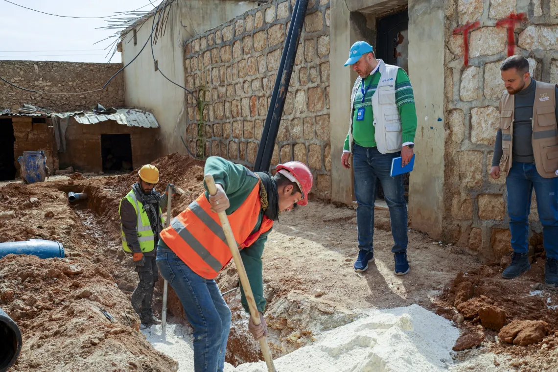 A UNICEF officer oversees work progress as workers carry out backfilling of a sewage channel.