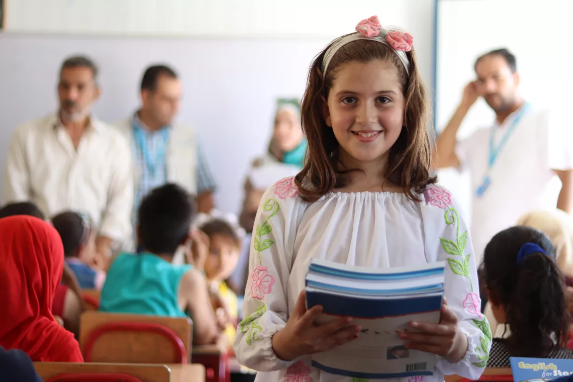 school girl holding textbooks in a classroom