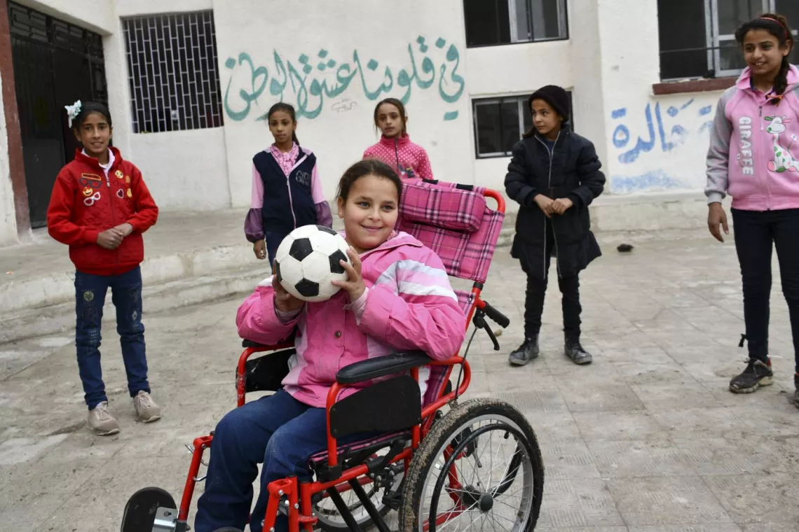 A girl in wheelchair holding a football in her hands