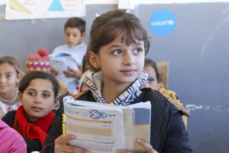 A young girl reads from her book in class