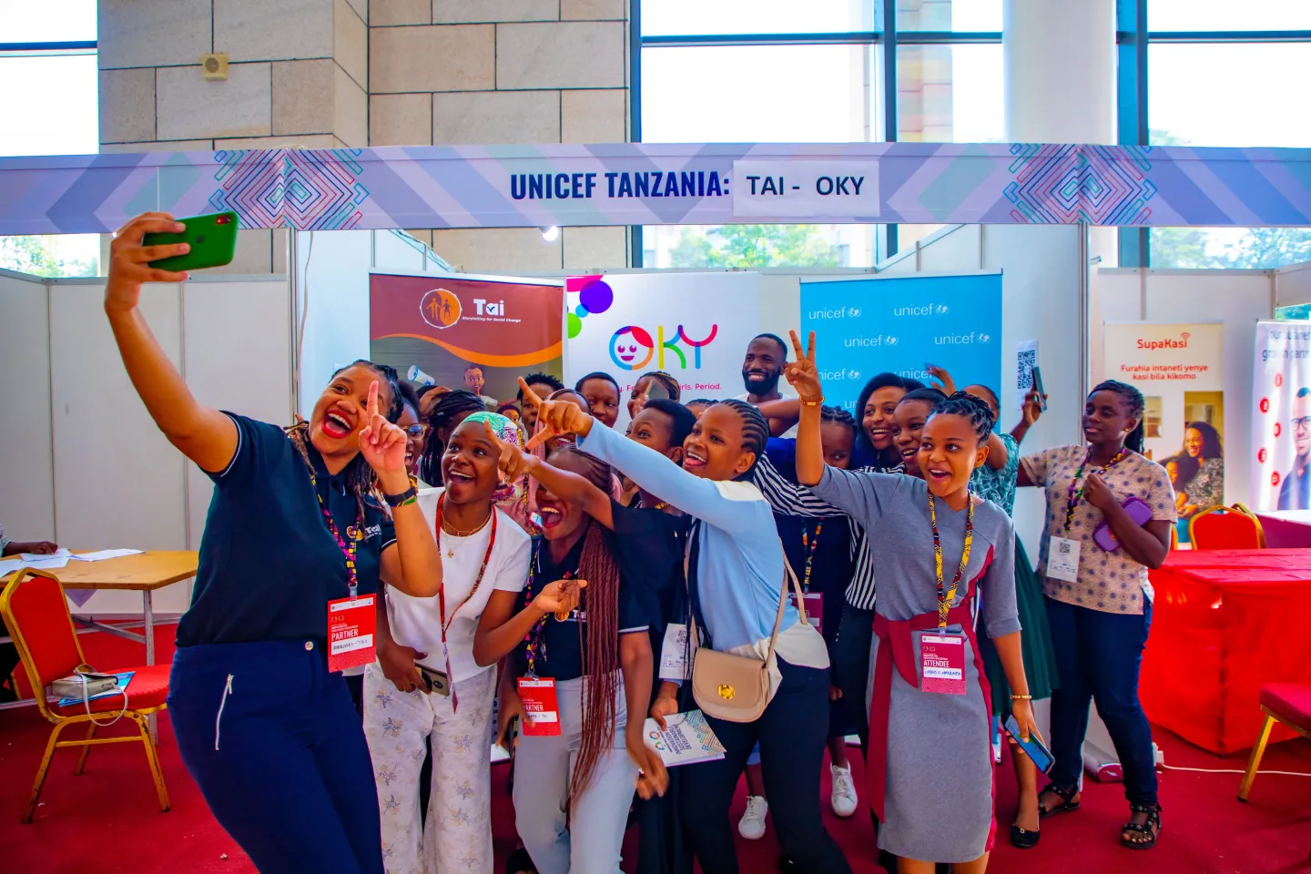 A group of girls take a selfie together at the UNICEF and Tai Tanzania booth