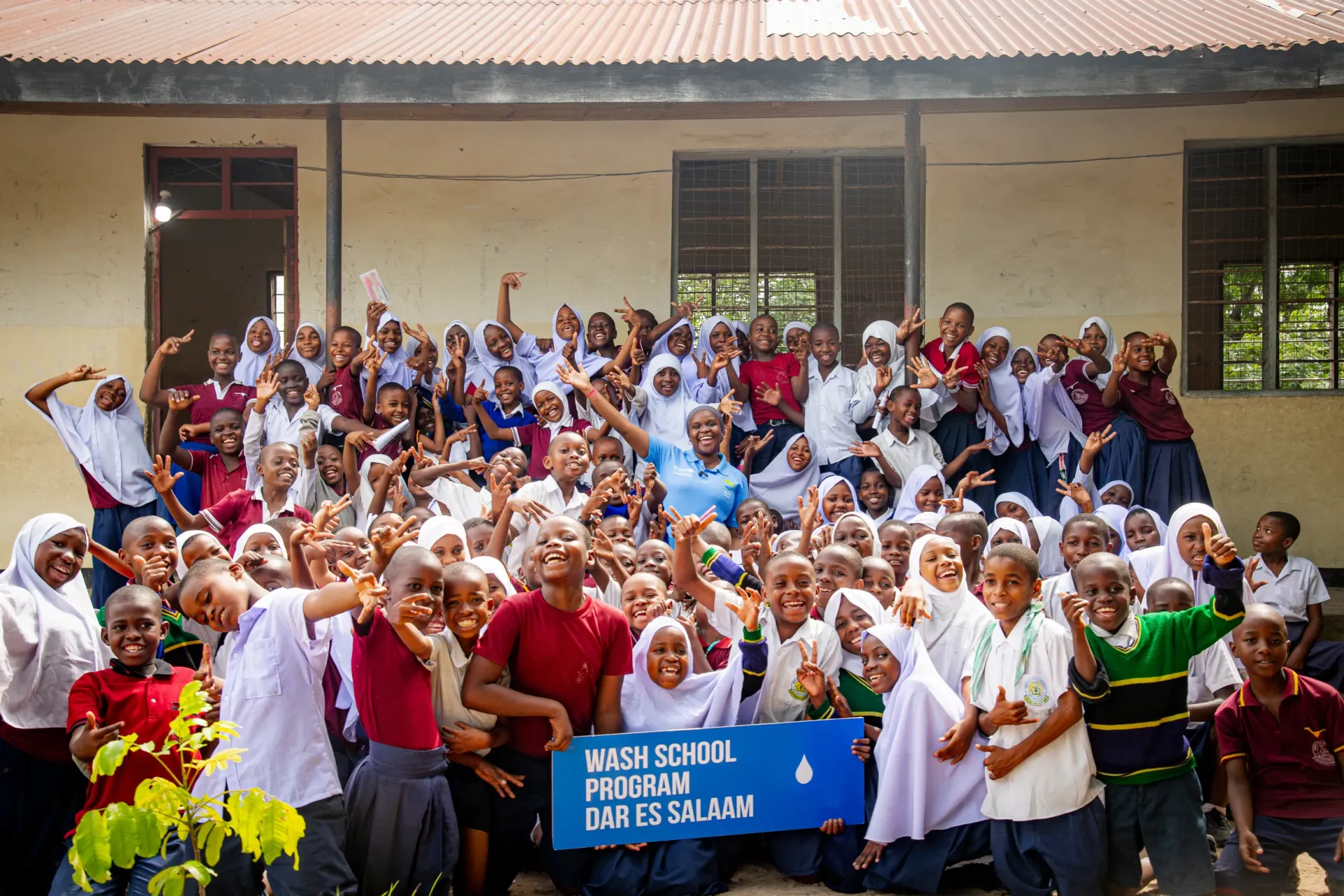 Madina Kimaro stands with the young WASH ambassadors at Mtongani Primary School 