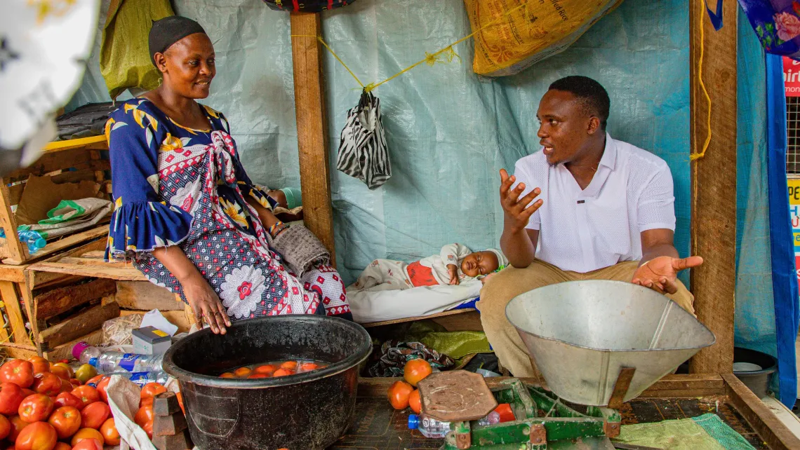 Mwiga Matthew, who manages Zakhem Market, talks with Salome at her stall.