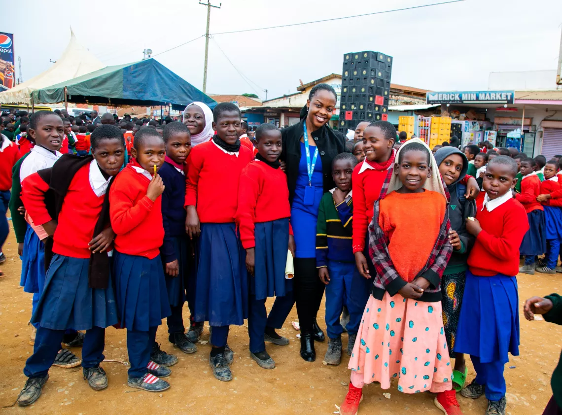 Chief of the Mbeya, Iringa and Njombe Field Office stands with students from the Njombe region who have come to the launch to learn more about nutrition.