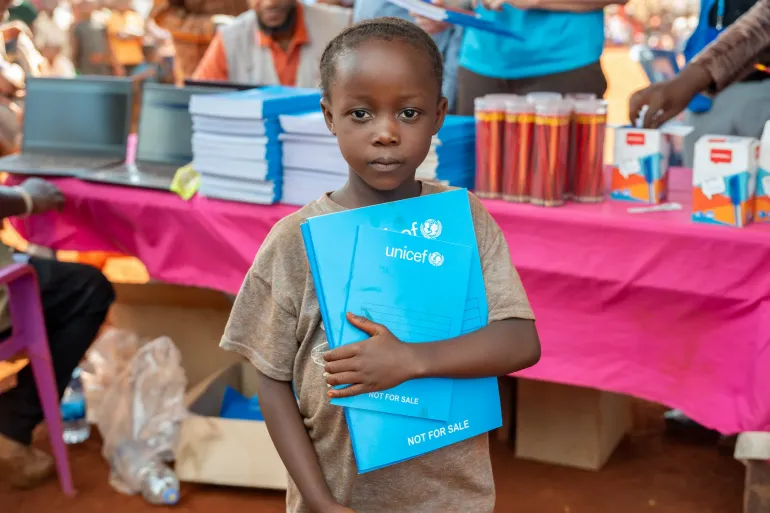 Refugee girl holding her new exercise books and writing materials at Nyarugusu camp.
